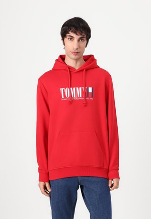 Red hoodie made of cotton blend fabric. Features a front kangaroo pocket, drawstrings, and a graphic logo on the chest.