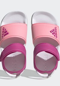 Sandále Adidas v ružovo-fialovom prevedení s dvoma nastaviteľnými popruhmi, textúrovanou stielkou a logovými akcentmi na popruhu a podrážke.