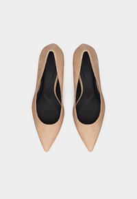 Ζευγάρι μπεζ μπαλαρίνες από σουέτ με μυτερή μύτη και μαύρα πέλματα, φωτισμένες από ψηλά σε λευκό φόντο.