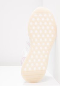 Ljusrosa och vita sneakers med en texturerad gummisula med hexagonalt mönster, mjuka mockadetaljer och zigzagmönster.