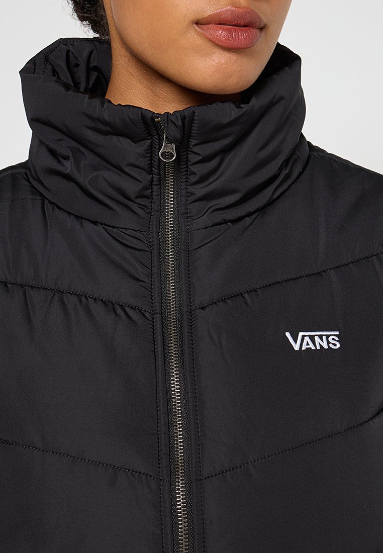 Giacca a vento nera con colletto alto, zip frontale argentata e logo "VANS" bianco sul petto. Materiale testurizzato e isolato con design trapuntato.