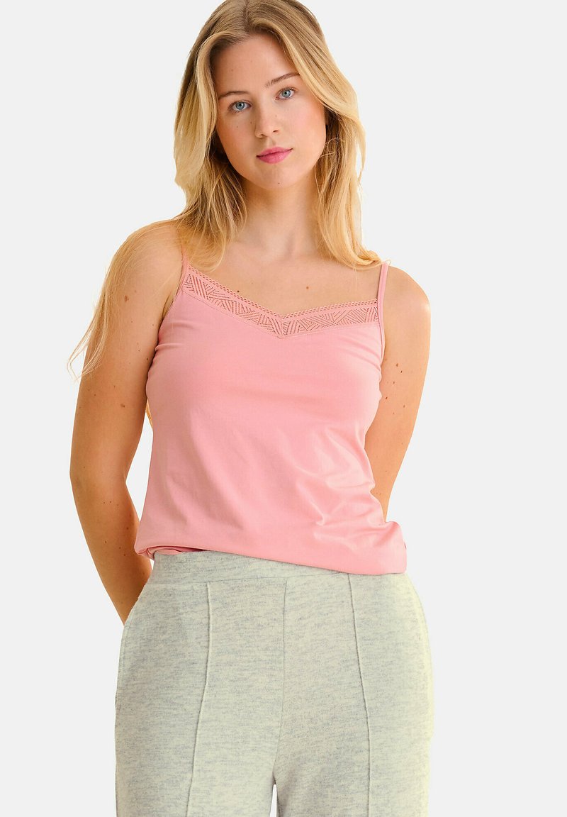 Haut sans manches rose clair avec des détails en dentelle délicate le long de l'encolure, fabriqué en tissu doux. Assorti à un pantalon gris texturé.