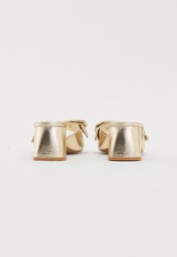 Gullfargede metallblokkhelsandaler med teksturert finish og en sløyfe detalj bak. Åpen tå-design, solid hel, glatt såle.