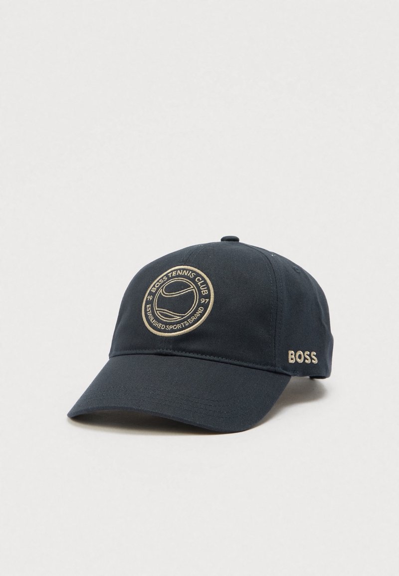 Casquette de baseball noire avec un logo circulaire beige du club de tennis à l’avant et « BOSS » brodé sur le côté.