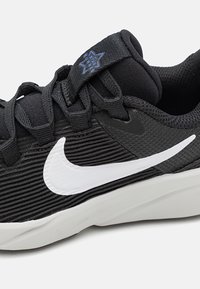 Crni Nike trkački tenisici s bijelim swoosh logom, mrežastim materijalom i tekstom "Star Runner" na tabu jezika, prikazujući bočne i gornje detalje.