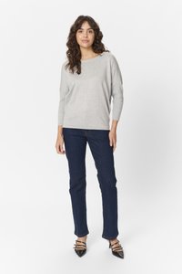 Svetlo siva pletena pulover s čolnasto ovratnico, dolgi rokavi, temno modri ravni kavbojke in črne pete z usnjenimi trakovi.