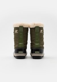 Stivali in tessuto verde con rivestimento in ecopelliccia, suole in gomma nera e marchio Sorel. Presentano accenti verticali verdi e un design impermeabile.