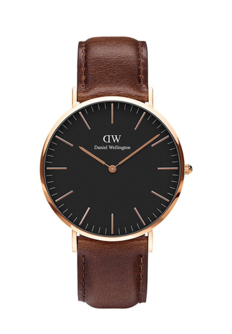 Reloj analógico redondo con una esfera negra, manecillas doradas y correa de cuero marrón. Presenta marcadores de hora minimalistas. Nombre de la marca en blanco.