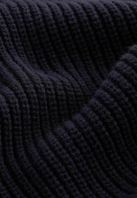 Navy blue knitted fabric with a ribbed texture, featuring soft, fuzzy strands creating a wave pattern across the surface.
