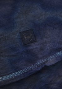 Blå gradientstoff med en myk tekstur, med en liten svart "Buff" logo-lapp og kontrasterende søm langs kanten.