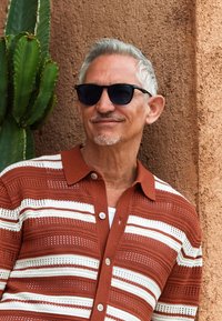 Knitted shirt with reddish-brown and white horizontal stripes, featuring a collared neck, button front, and open weave texture.