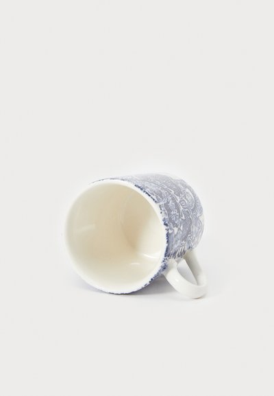 Tazza in ceramica bianca con un intricato motivo floreale blu sulla parte esterna, leggermente inclinata, che mostra una finitura liscia e lucida e un manico rotondo.