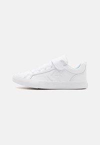 Baskets de sport blanches avec une finition en cuir lisse, bout rond, semelle plate en caoutchouc, lacets à l'avant et strap en Velcro. Emblème en forme d'étoile sur le côté.