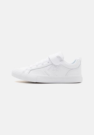 Baskets de sport blanches avec une finition en cuir lisse, bout rond, semelle plate en caoutchouc, lacets à l'avant et strap en Velcro. Emblème en forme d'étoile sur le côté.