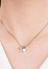 Zilveren ketting met twee hartbedels: de ene glad en glanzend, de andere versierd met kleine heldere steentjes, aan een delicate ketting.