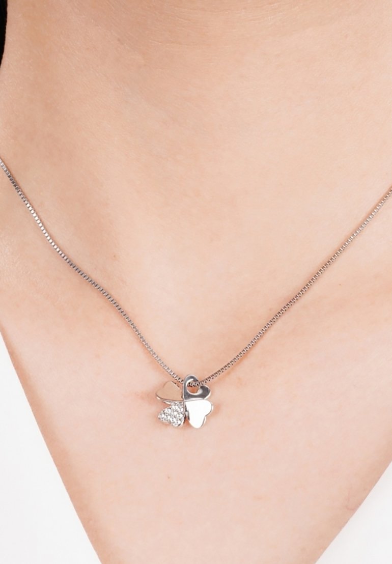 Zilveren ketting met twee hartbedels: de ene glad en glanzend, de andere versierd met kleine heldere steentjes, aan een delicate ketting.