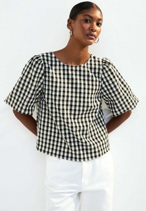 Black and white gingham check top with short puff sleeves and a round neckline, made from textured fabric, paired with white pants.