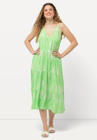 Zelené maxi šaty s vrstvovým designem, zahrnující V-výstřih a bílé abstraktní vzory. Lehce splývavá tkanina vhodná na teplé počasí.