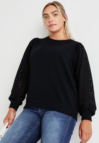 Black sweatshirt featuring solid body and textured, patterned puff sleeves, made from soft fabric with ribbed cuffs and hem.
