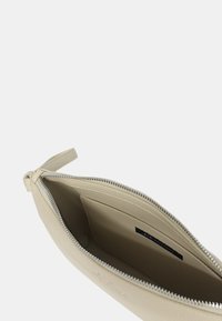 Clutch in pelle beige con una finitura liscia, chiusura con zip e fodera in tessuto. L'interno presenta un piccolo etichetta del marchio e ampio spazio per gli accessori essenziali.