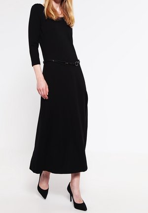 Czarna długa sukienka z długim rękawem, kwadratowym dekoltem i dopasowaną talią, podkreślona czarnym paskiem. Gładka faktura i długość do podłogi.