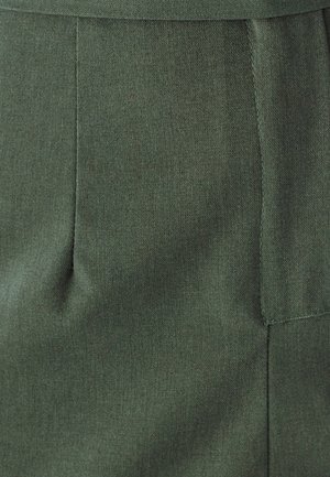 Tamnozeleni materijal s suptilnom teksturom; sadrži dizajn s ušivenim nabora i vidljive šavove, ističući strukturirani oblik.