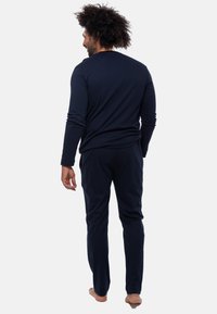Navy blauw langermige top met een aansluitend ontwerp, gecombineerd met bijpassende slim-fit broek. Stof lijkt zacht en licht van gewicht met een gladde textuur.