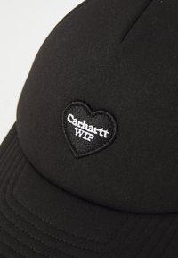 Black cap made of fabric with a textured surface. Features a heart-shaped embroidered patch with "Carhartt WIP" in white.