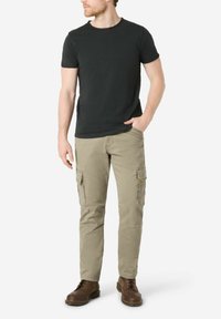 Black short-sleeve t-shirt paired with beige cargo pants featuring side pockets and a straight fit, complemented by brown lace-up boots.