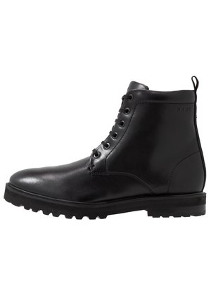 Botín negro de cuero con cordones delanteros, suela gruesa y texturizada, y lengüeta en el talón para facilitar el calzado.