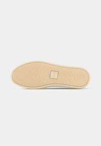 Shoe outsole made of rubber, featuring a textured surface with horizontal grooves. Light beige color with a rectangular logo in the center.