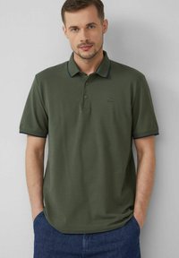 Polohemd aus olivgrünem Baumwollstoff mit einem klassischen Kragen, marineblauen Akzenten an Kragen und Ärmeln sowie einem kleinen Logo auf der Brust.
