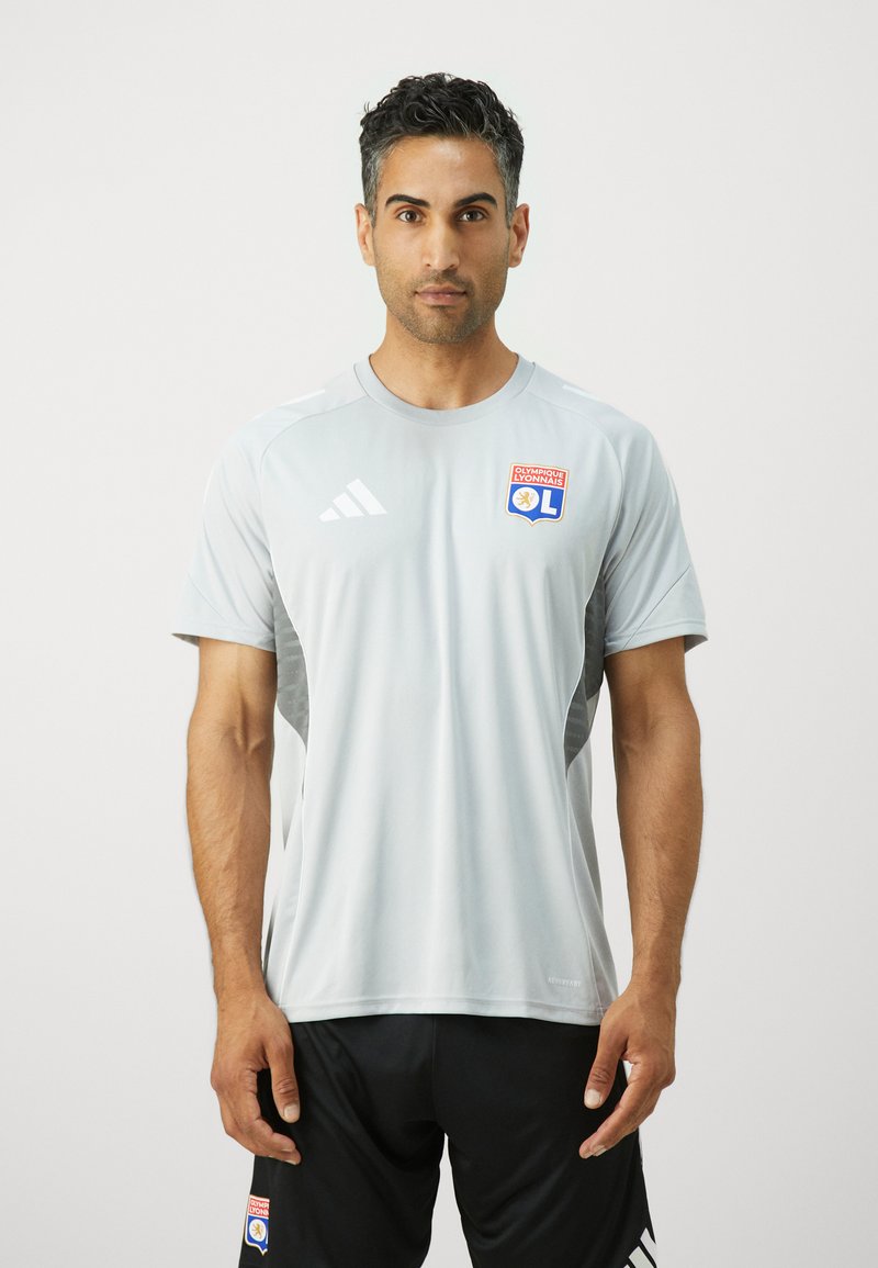 Heledane hall t-särk lühikeste varrukatega, millel on Olympique Lyonnais logo ja mustad aksendid. Valmistatud niiskust hülgavast kangast.