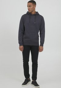 Haut à capuche gris foncé en tissu doux, avec une poche avant, un capuchon à cordon de serrage ajustable et des poignets côtelés, associé à un pantalon noir slim-fit.