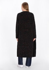 Cardigan lungo nero con un motivo testurizzato, caratterizzato da macchie multicolori distribuite su tutta la superficie, e una vestibilità ampia che si estende oltre i fianchi.