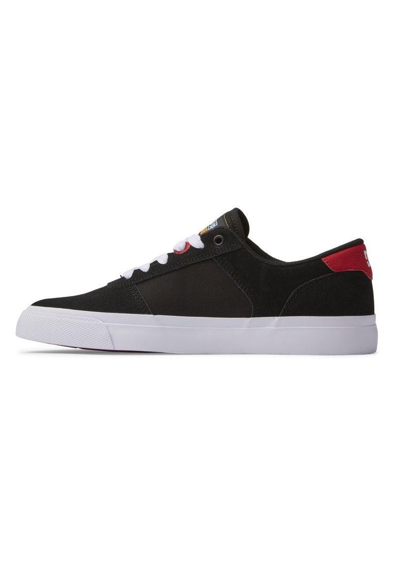 Schwarze Sneaker mit Obermaterial aus Stoff, weißen Schnürsenkeln, roten Akzenten an der Ferse und einer weißen Gummisohle. Verfügt über eine Steppnaht und Logodetails auf der Zunge.