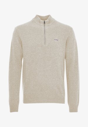 Beige színű, cipzáros nyakú pulóver texturált kötött anyagból. Fekete cipzárral és egy kis logóval rendelkezik, amely piros, fehér és kék csíkokból áll, és a mellrészen található.