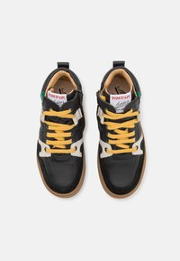 Zwarte en witte leren sneakers met gele veters, getextureerde oppervlakken en een gumrubberen zool. Bevat ritsen en branding op de tong.