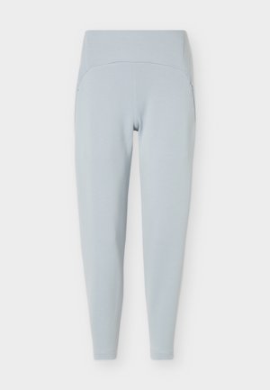 Gaiši zili legingi ar augstu vidukli un šauru piegriezumu, ar sānu kabatām, attēloti plakani uz balta fona.