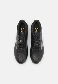 Scarpe da ginnastica nere con tomaia texturizzata realizzata in materiale sintetico, dotate di lacci neri, dettagli dorati e design aerodinamico.