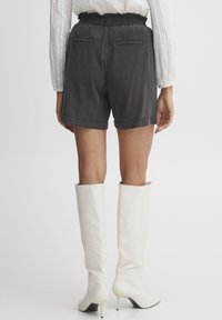 Gray shorts with a textured fabric, elastic waistband, and two back pockets, paired with tall white heeled boots.