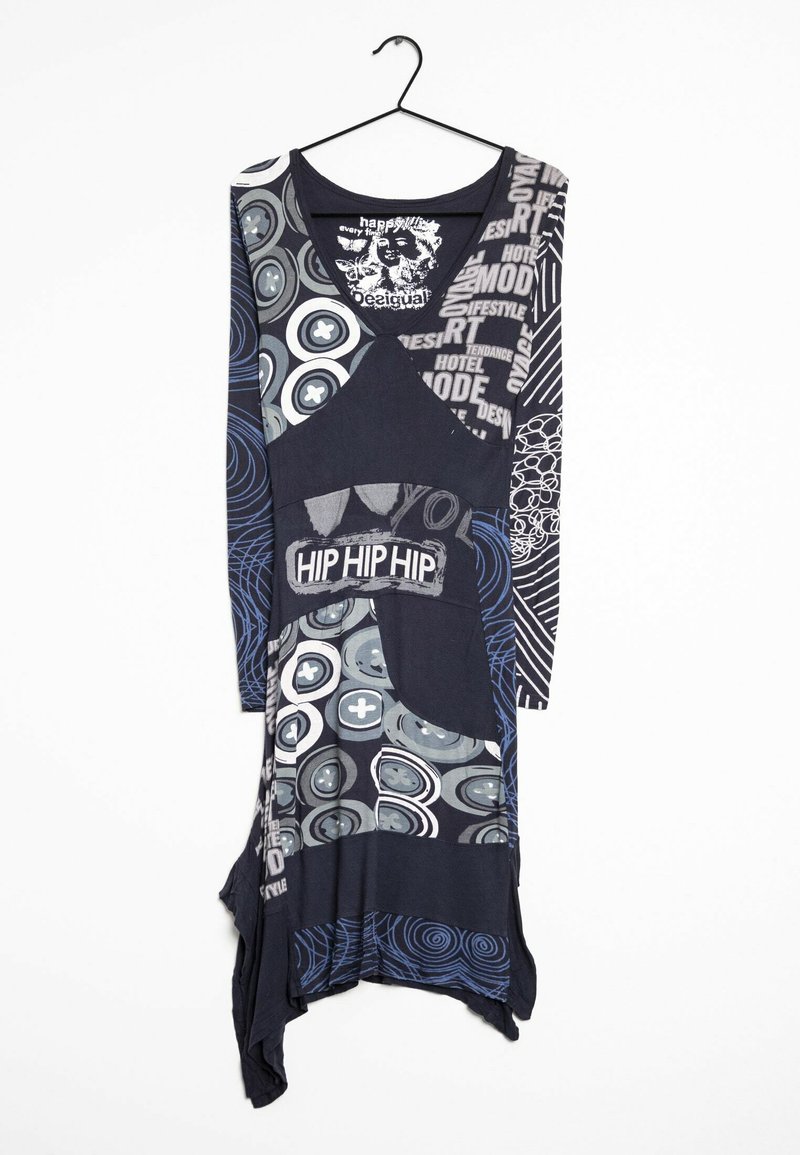 Långärmad, flerfärgad tunika med varierande grafiska mönster, djup halsringning och asymmetrisk fåll, främst i mörkblå och grå nyanser.