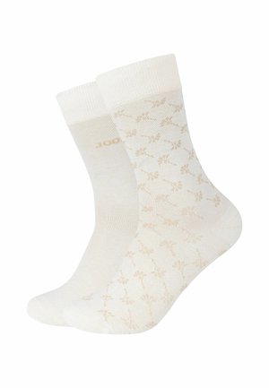 Deux chaussettes blanches mi-mollet, l'une avec des motifs floraux beiges subtils et l'autre unie avec un texte discret près du bord supérieur.