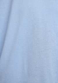 Lyseblå stof med synlig tekstur og bløde folder, der viser et glat, vævet bomuldsmateriale.