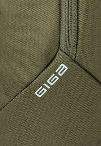 Nahaufnahme eines strukturierten olivgrünen Stoffes mit weißem "GIGAB"-Logo und sichtbaren Nähten entlang der Nähte.