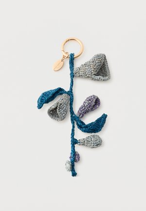 Złoty brelok przyczepiony do niebieskiego szydełkowanego szypułki z szarymi, fioletowymi i niebieskimi szydełkowymi liśćmi i pąkami.