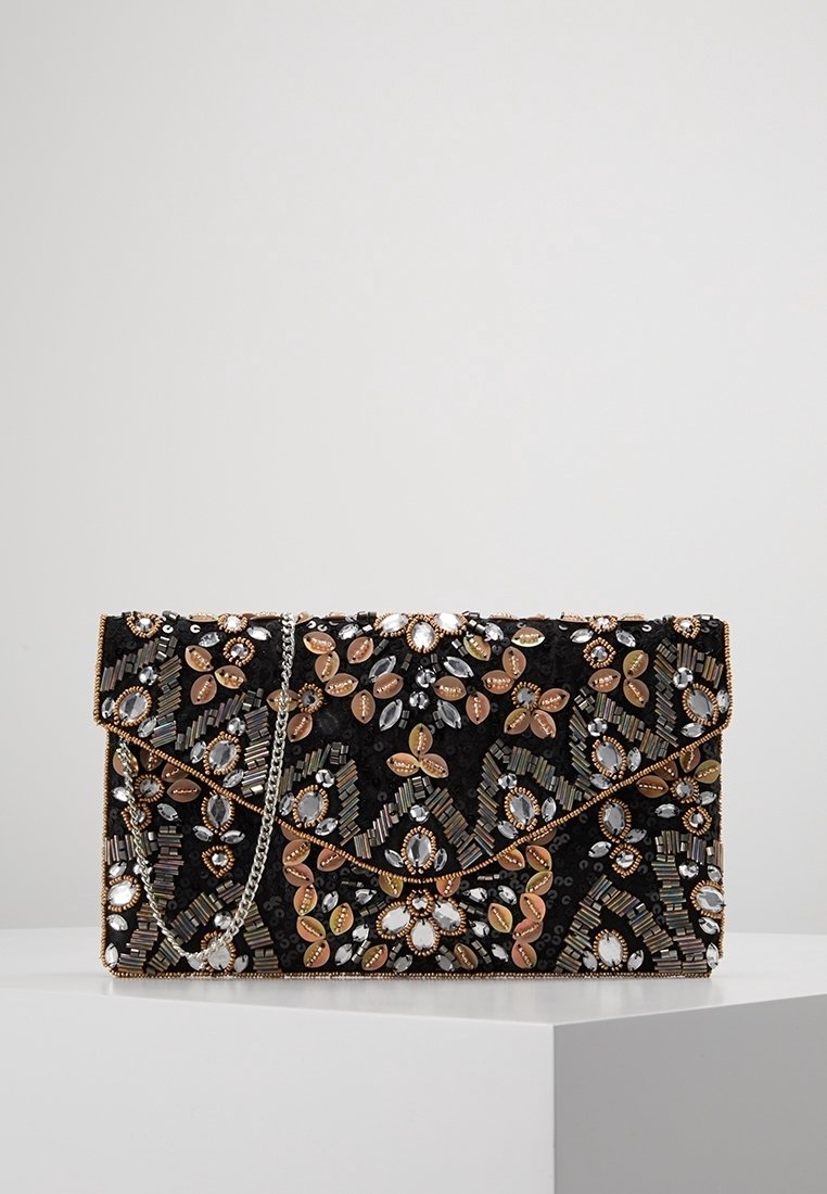 Czarna kopertówka z misternymi zdobieniami, zawierająca metaliczne i kamieniowe akcenty, składana klapa oraz srebrny łańcuszkowy pasek.