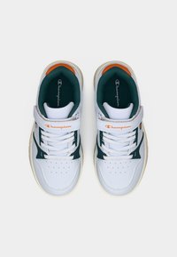 Λευκά αθλητικά παπούτσια με πράσινες και πορτοκαλί λεπτομέρειες. Κατασκευασμένα από λείο συνθετικό υλικό με διάτρητη μύτη και ιμάντα με βέλκρο πάνω από τα κορδόνια.