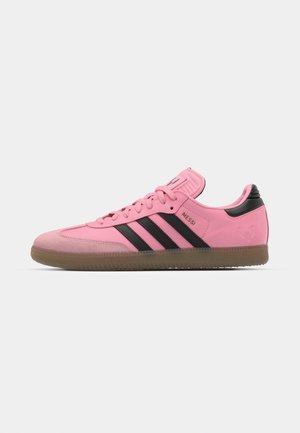 Pink athletic shoes with black stripes and accents. Features a textured upper, round toe, and a gum sole. Lacing system with padded tongue.