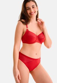 Ensemble de soutien-gorge rouge et culotte taille haute en matériau doux; le soutien-gorge présente des panneaux transparents et du matériel décoratif sur les bretelles.
